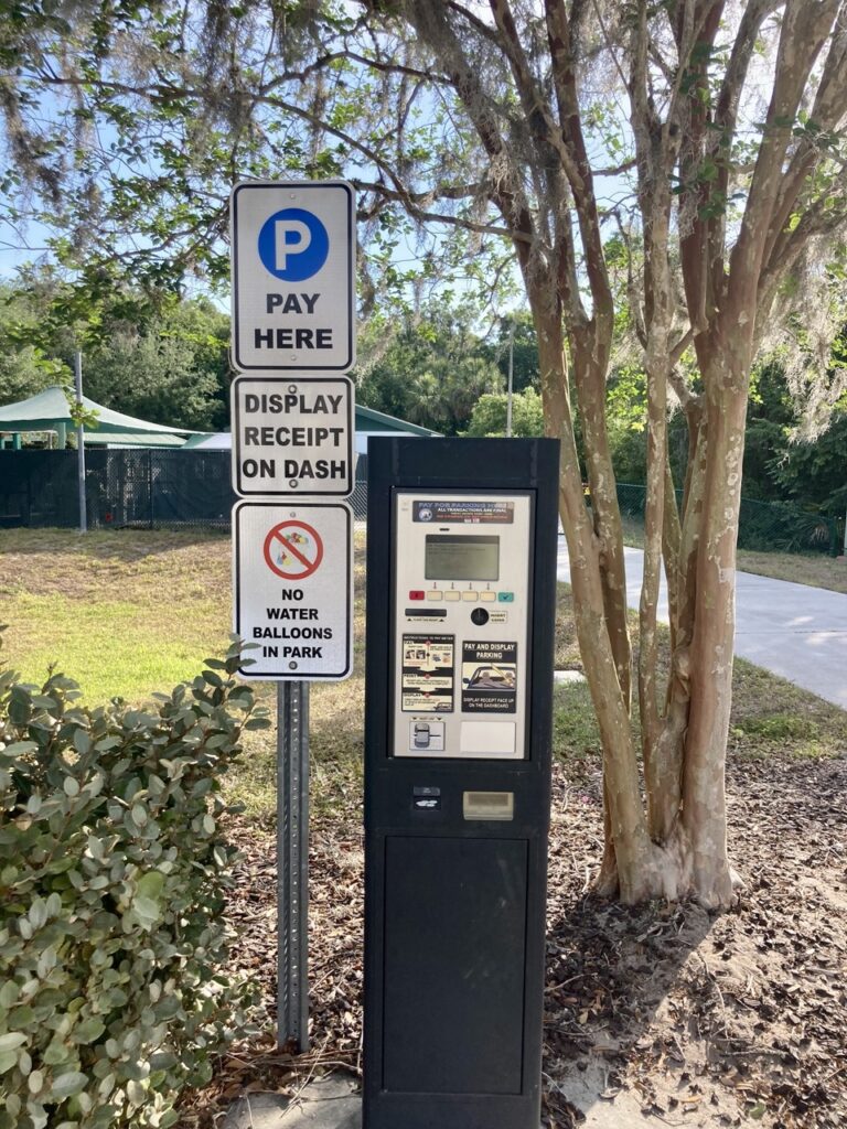 parking payment kiosk next to a tree