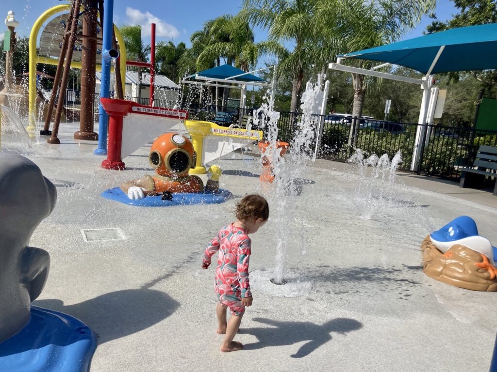 toddler in front of fountains at the tarpon spring splash pad, including a sponge diver fountain