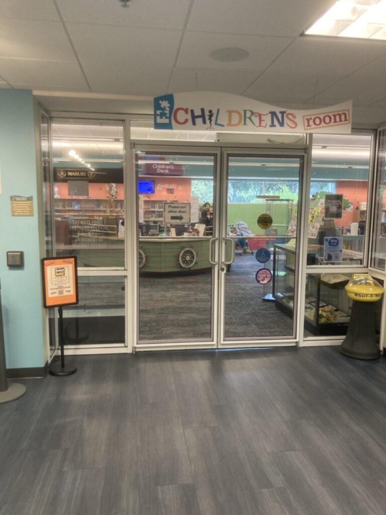 entrance to the children's library section at palm harbor library showing two glass doors and glass wall looking into the kids area