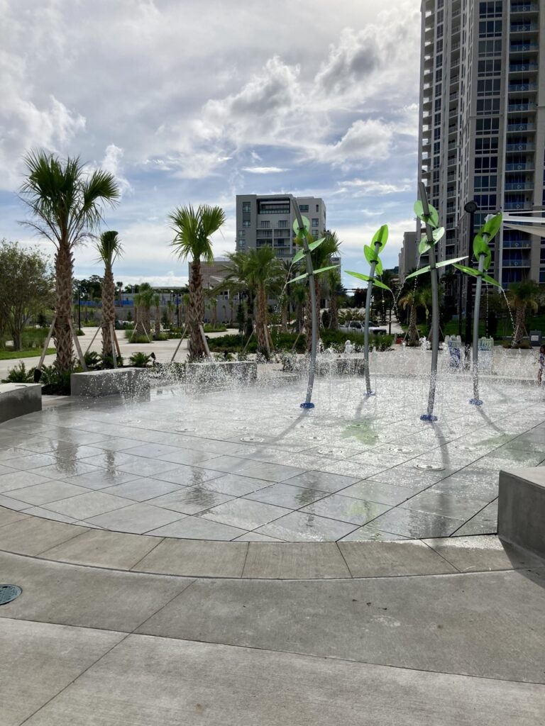 splash pad at coachman park in clearwater with fountains on and downtown buildings in the background