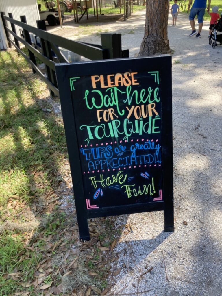 chalkboard sign at old mcmicky's farm saying to wait here for tour and that tips are appreciated