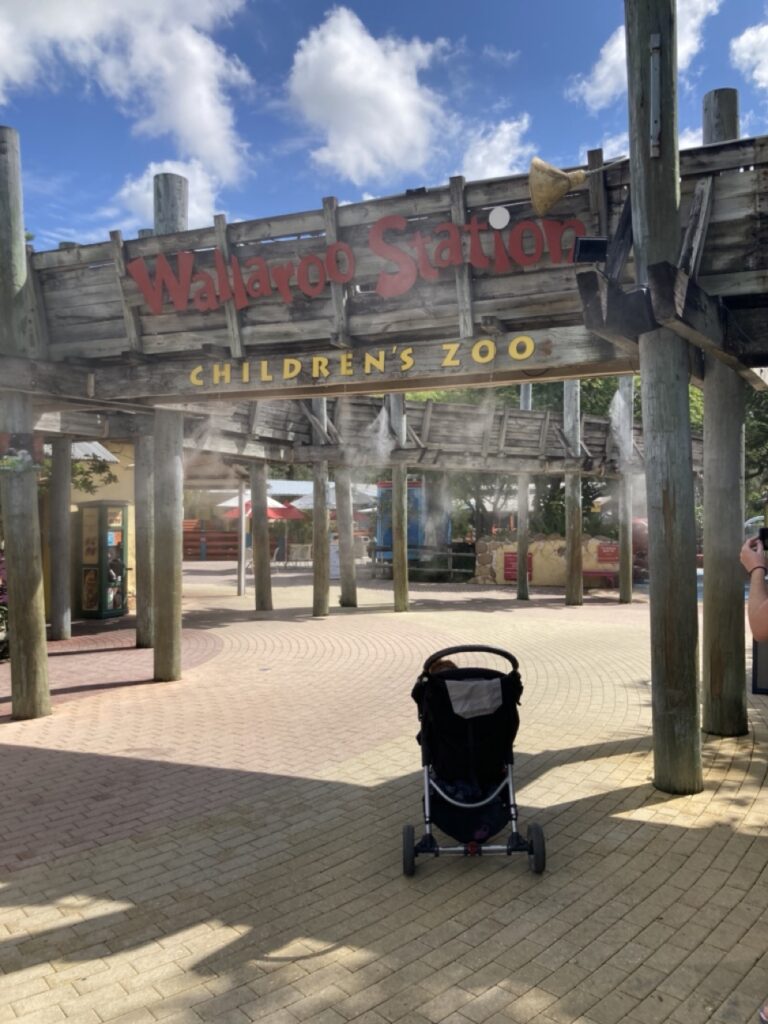 A stroller in front of a sign that says Wallaroo Station Children's Zoo at the Tampa zoo at Lowry Park