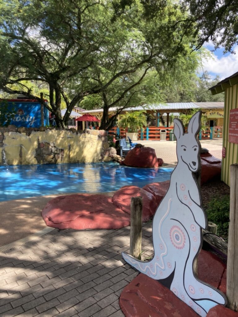 A kangaroo wood sign in the foreground and a splash pad in the background at ZooTampa