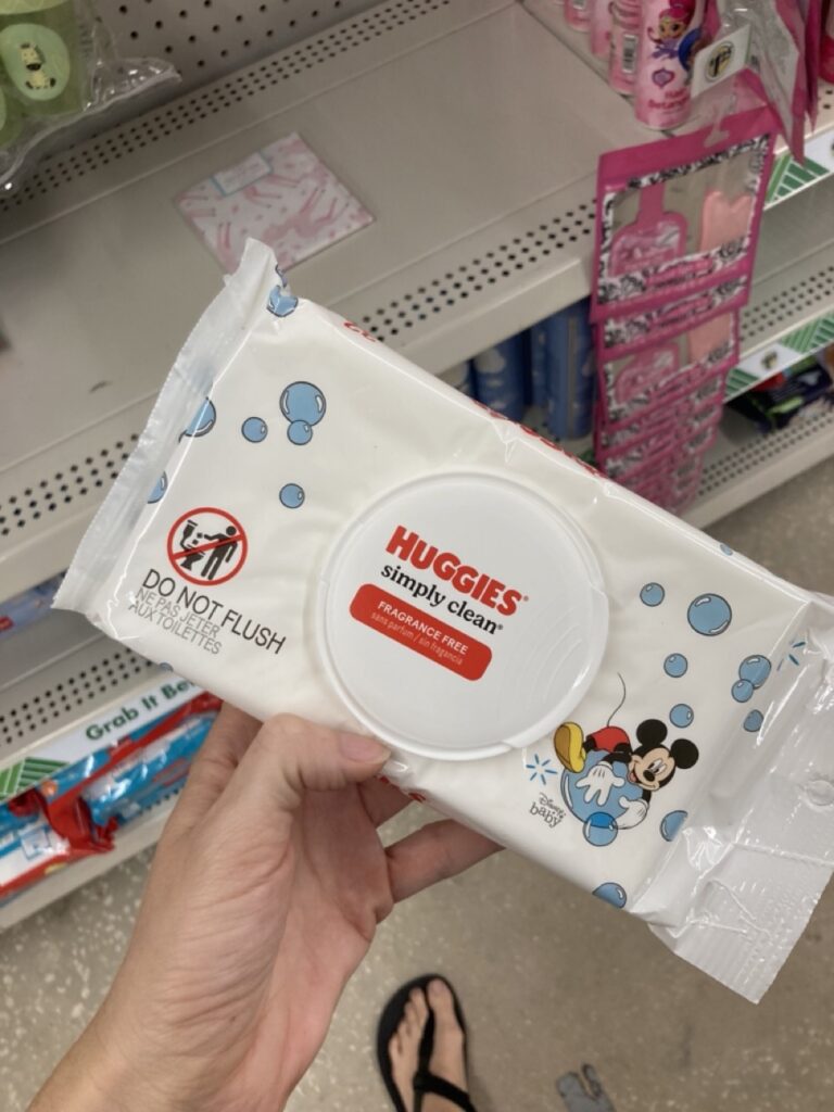 a hand holding up a pack of huggies wipes