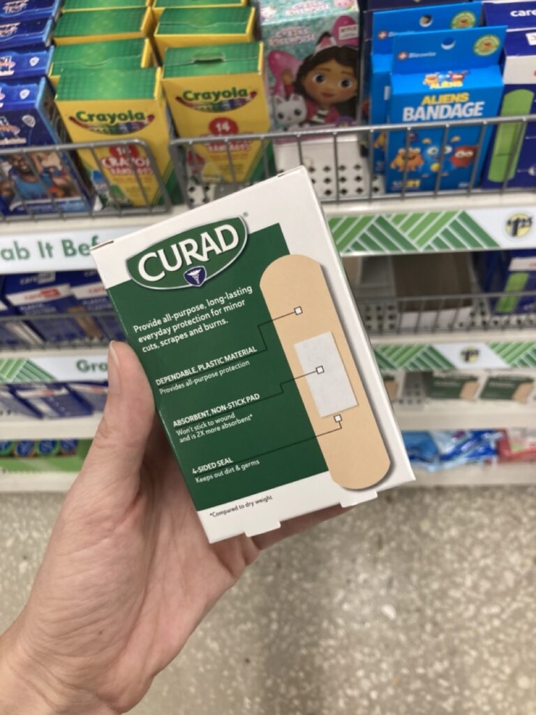 box of bandaids being held out by a hand