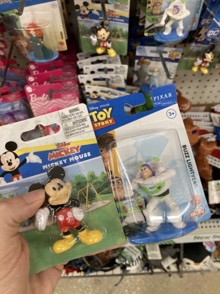 little mickey and donald figurines in packaging being held up by a hand at the dollar tree