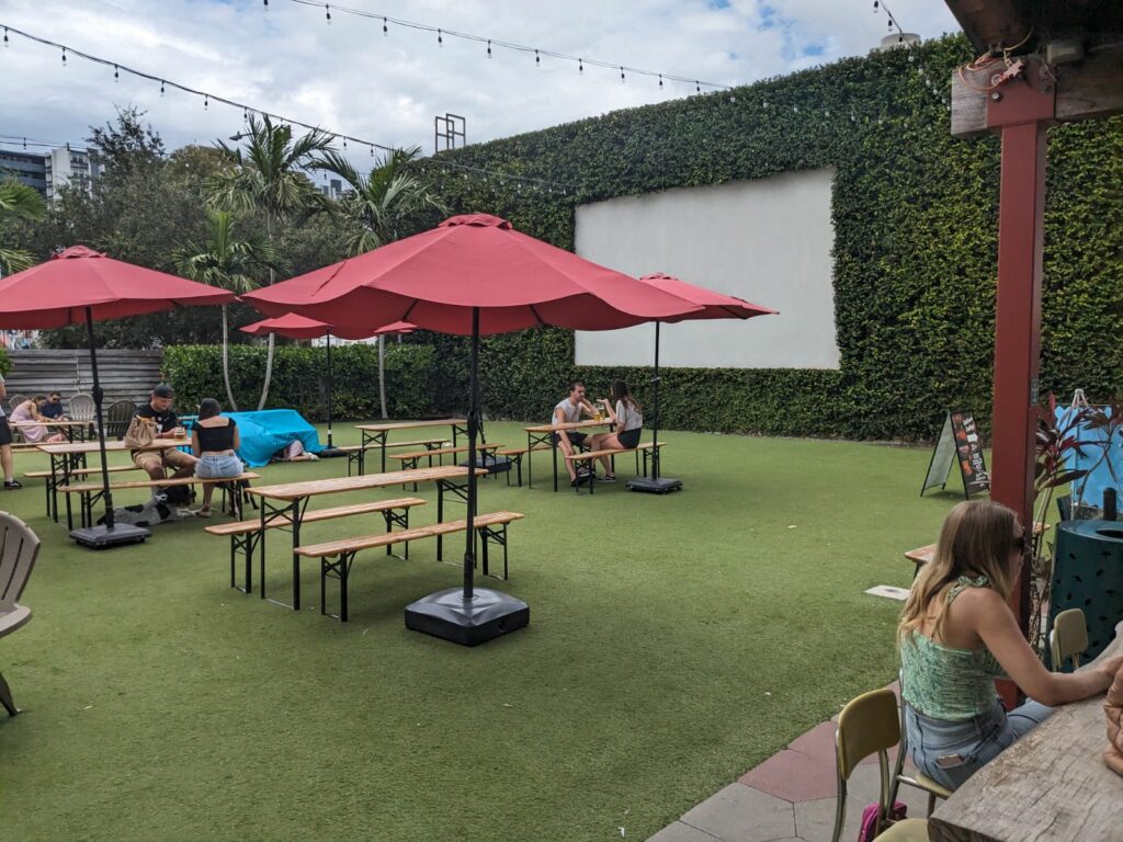 Outside turk grass lawn with tables with red umbrellas at Green Bench brewing in St Pete