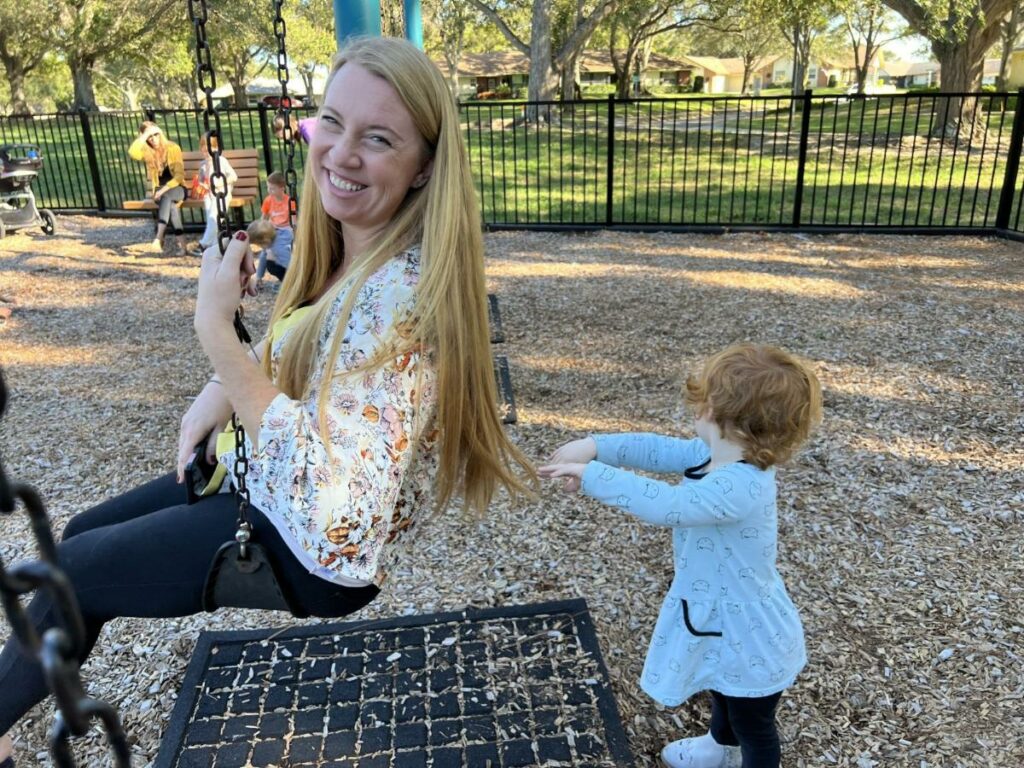 malena on a swing at the park with a toddler pushing her