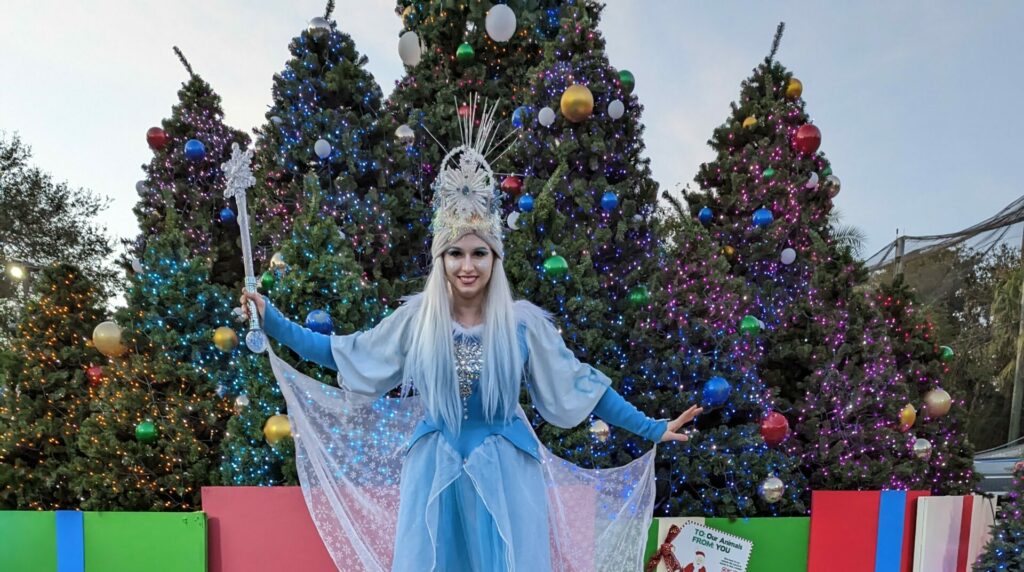 Winter princess standing in front of lit Christmas trees at Christmas in the Wild at ZooTampa