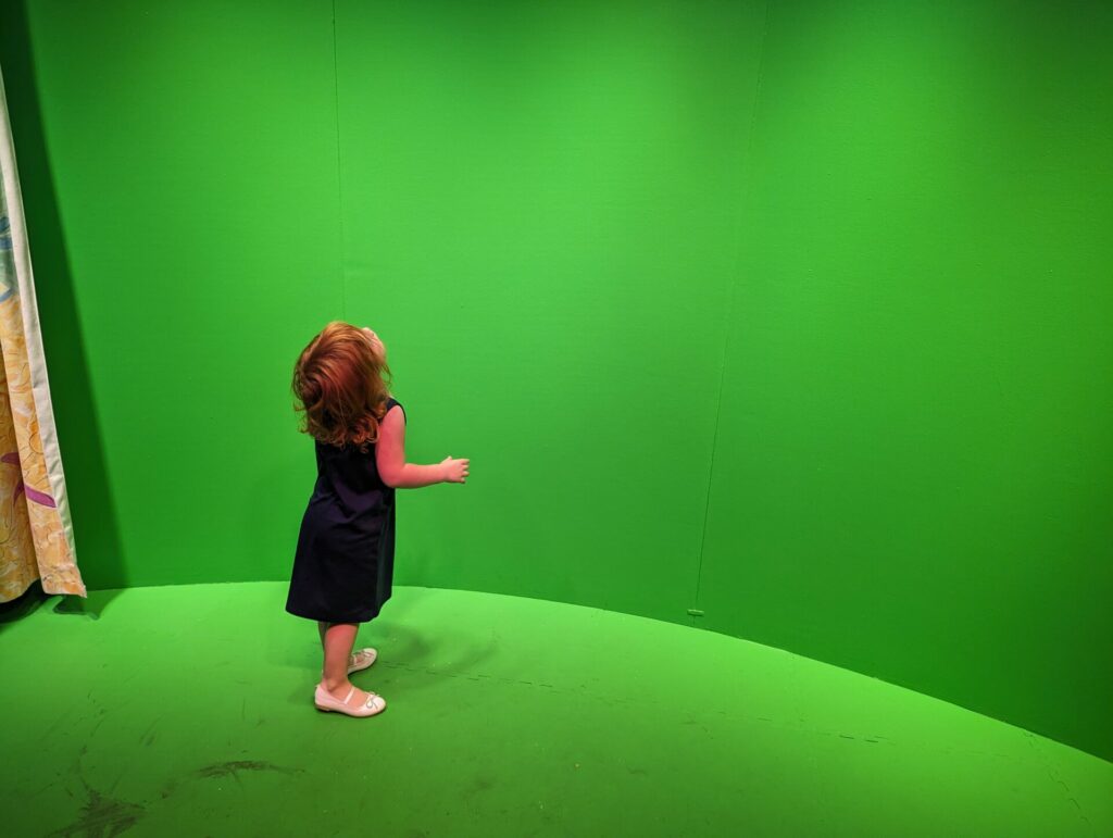Toddler in front of the green screen wall at the Children's Art museum in dunedin