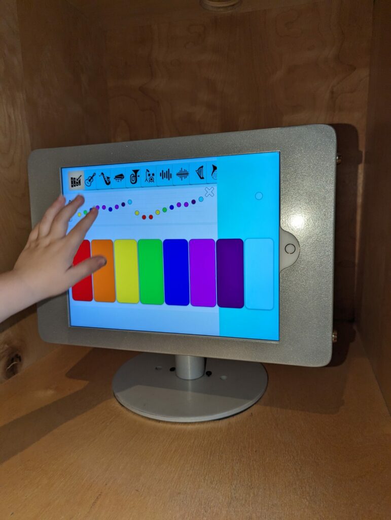 a table device with colors of the rainbow and a child's hand touching it