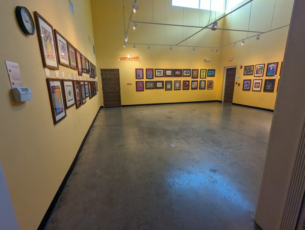 a museum room exhibiting student art in frames at a distance