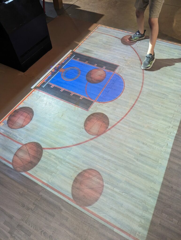 a basketball game that is projected on the floor that kids can play