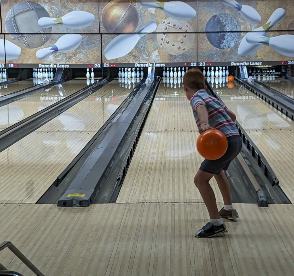 the back of a child getting ready to roll a bowling ball down a lane