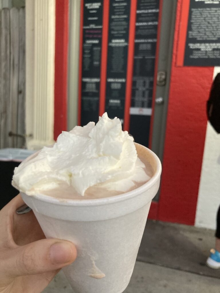 milkshake with whipped cream being held by a hand