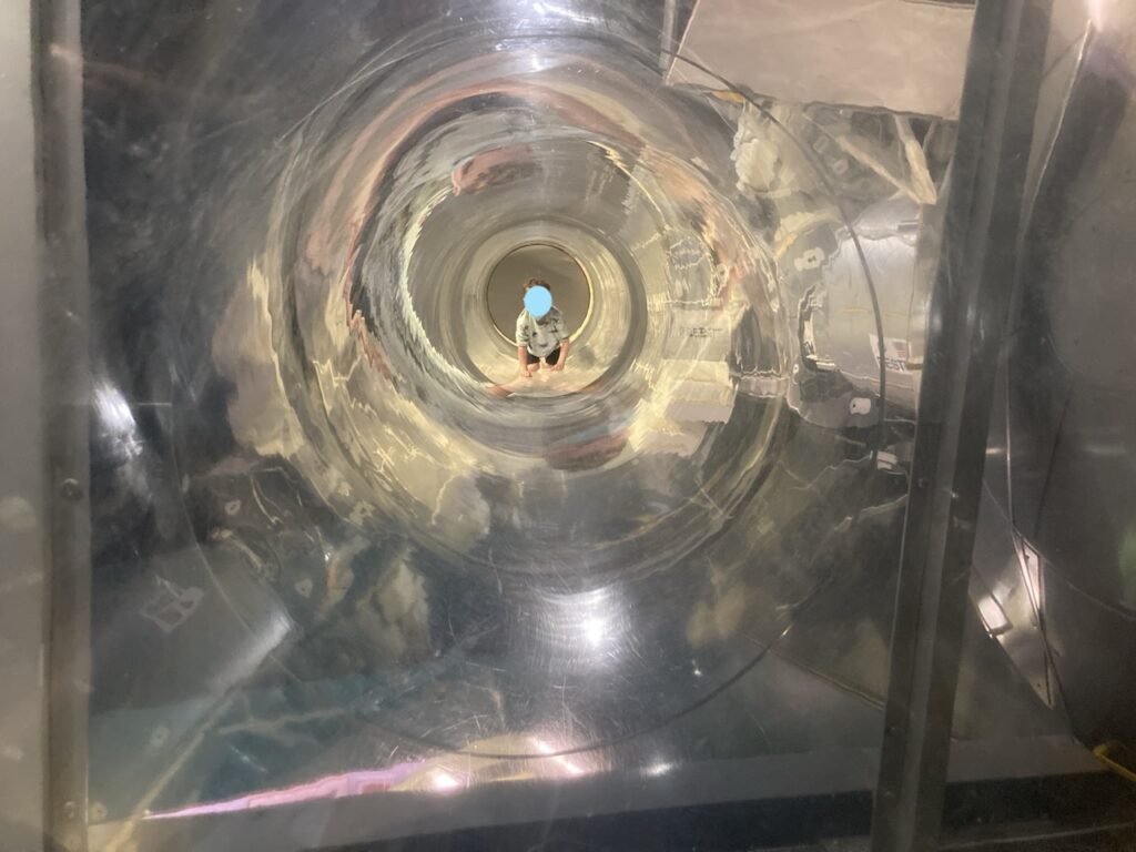 a toddler crawling through a clear tube at NASA