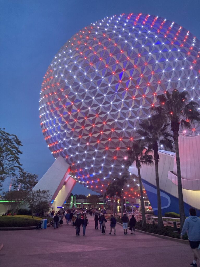 The epcot ball lit up with red strips at night