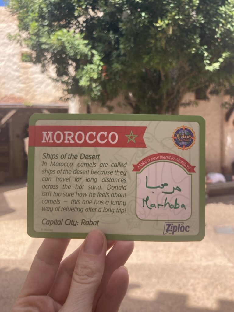 a hand holding up a kidcot epcot card for morocco with a little info blurb about the country on it