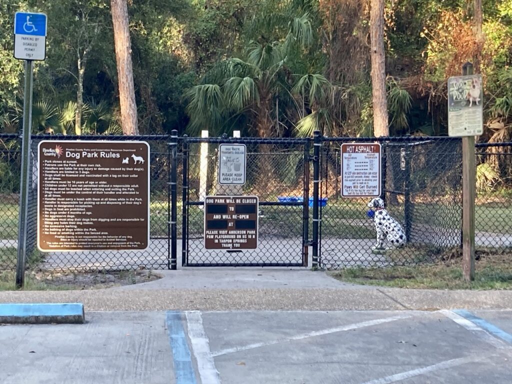 Entrance to john chestnut park dog park with a fence and posted rules signs