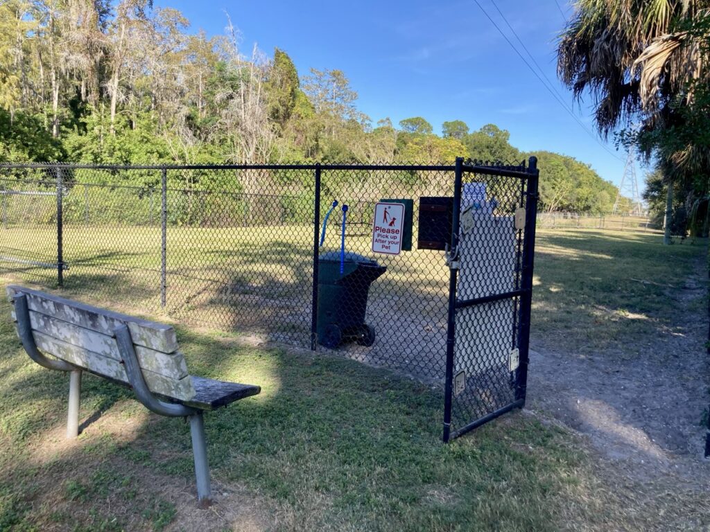 a bench and a fence with a large open field in the distance at the Safety Harbor dog run dog park
