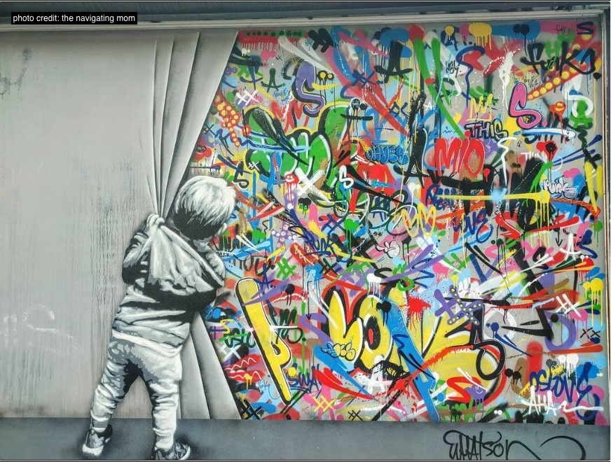 Graffiti of the back of a little kid pulling back a curtain to show a graffiti wall at Wynwood Walls in Miamia FL