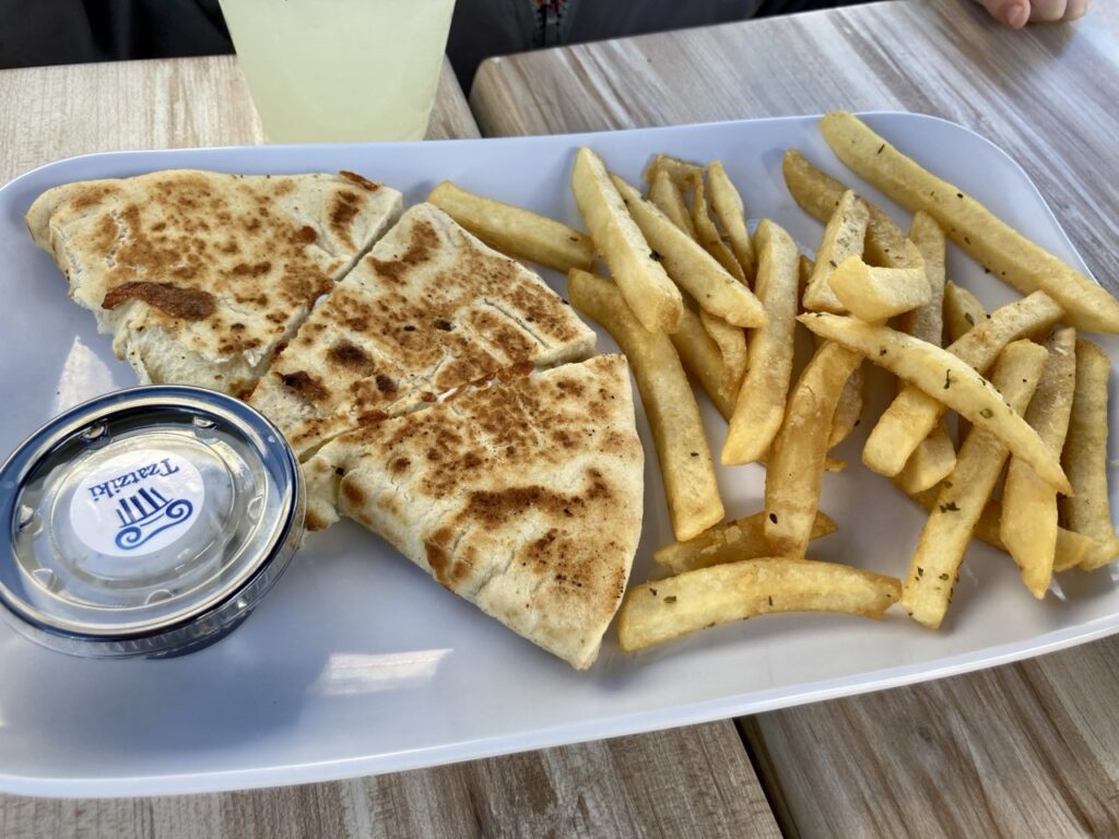 A pate of a sauce cup, a pita bread quesadilla and french fries