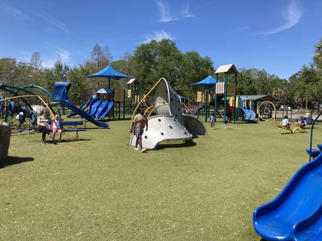 large playground field with playground structures spread throughout at dell holmes park in st petersburg fl