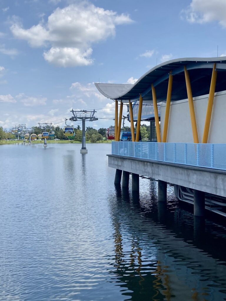 disney skyline station over the water with the skyliner lines and gondolas in the distance