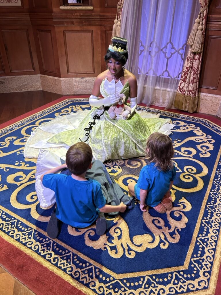 toddlers sitting in front of tiana at magic kingdom