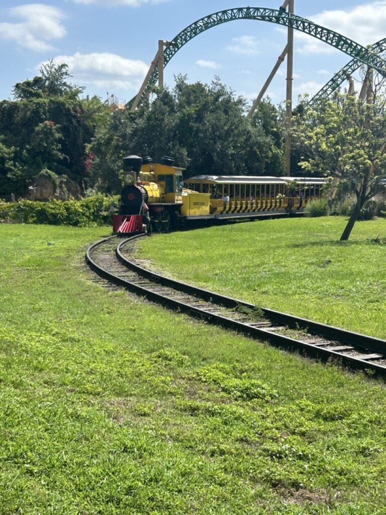 train coming around the track with a rollercoaster in the background at busch gardens